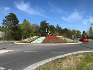 Begrünung eines Kreisverkehrs mit Rosen und Tulpen sowie Baumpflanzung im Hintergrund
